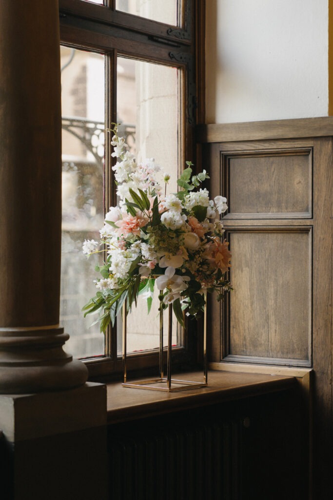 Florales Hochzeitsarrangement am Fenster einer eleganten Hochzeitslocation