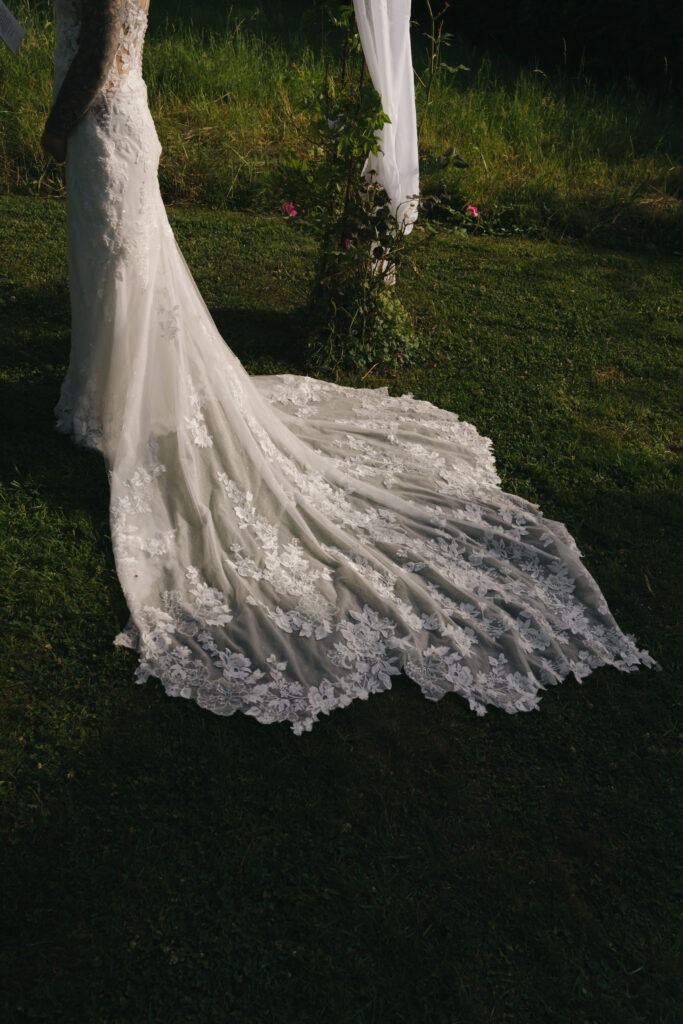 Brautkleid mit langer Spitzenschleppe bei einer Outdoor-Hochzeit – elegante Hochzeitsfotografie